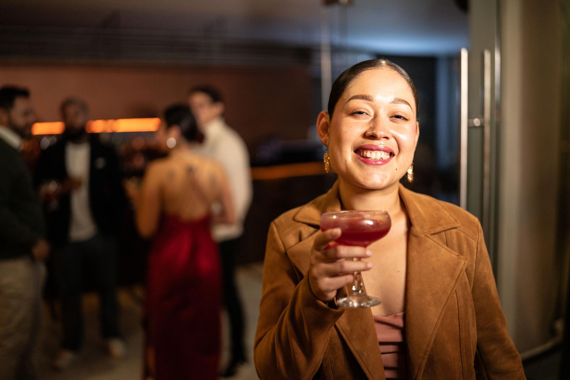 Portrait of a young woman holding a drink on party at bar