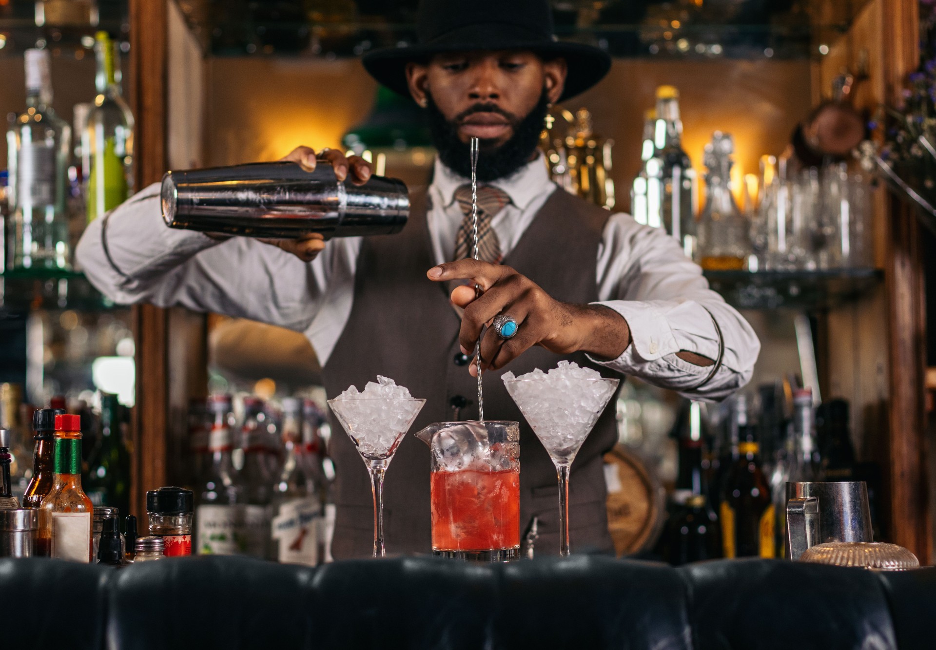Black bartender preparing a cocktail in a traditional cocktail bar